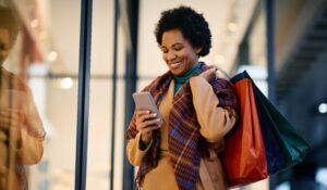 Mature woman shopping in store and also on her phone.