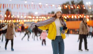 woman enjoys outdoor ice skating rink decorated with holiday lights